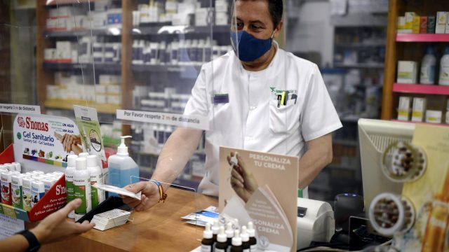 Un farmacéutico entrega a un cliente una de las mascarillas KN95 que ha recibido en su farmacia.