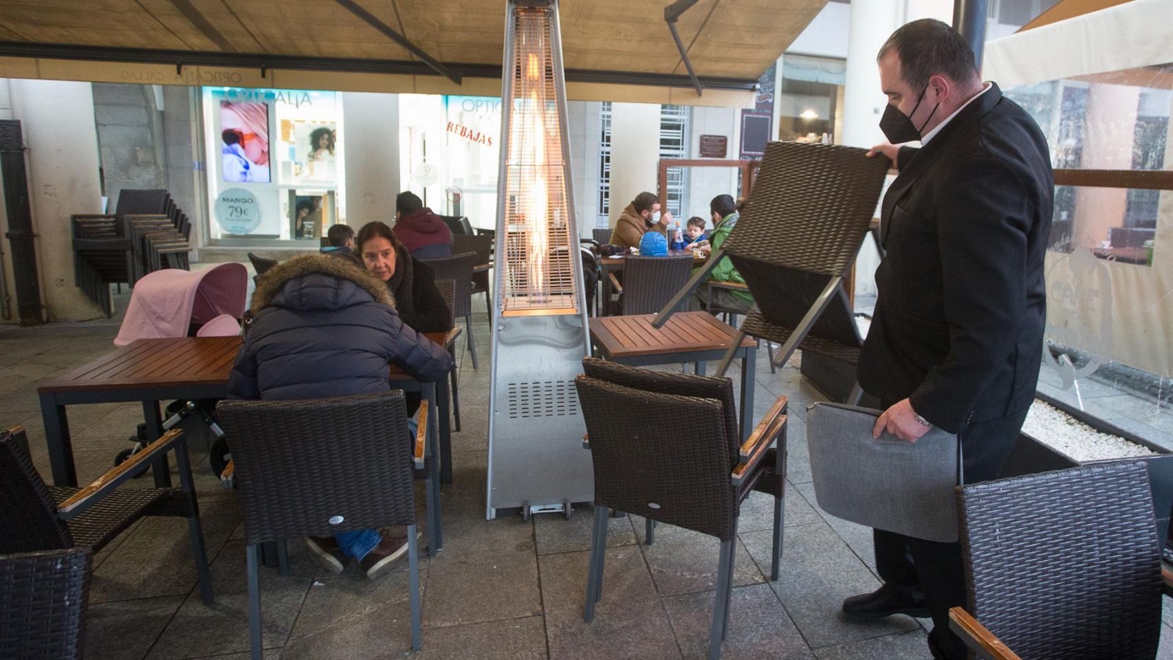 Un camarero recoge las sillas y mesas en un local de Lugo.