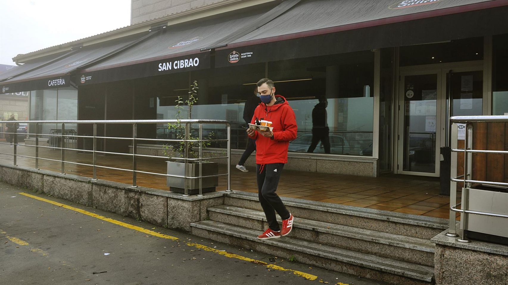 Un joven recoge un café de un establecimiento abierto en San Cibrao das Viñas.