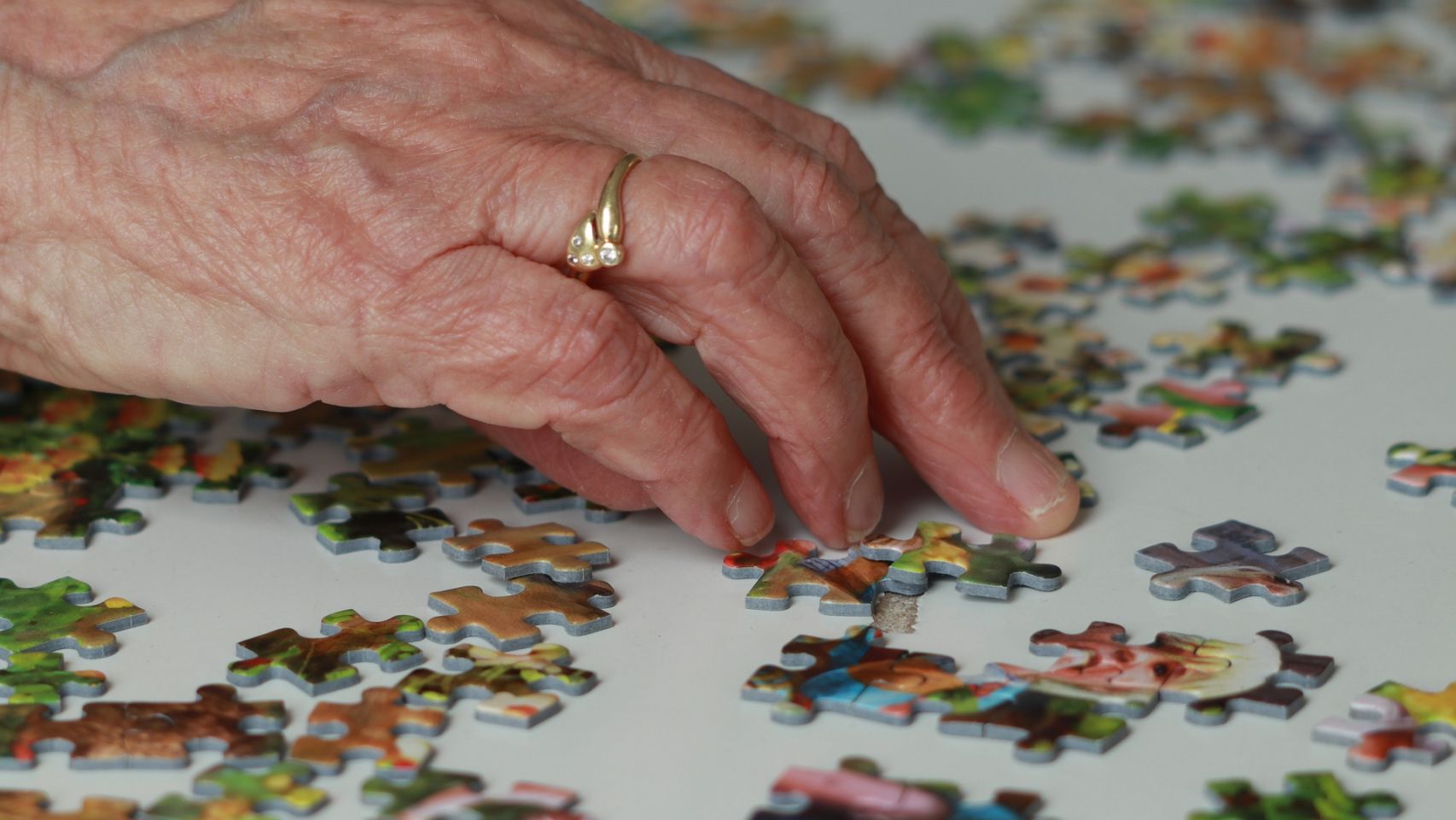 Una persona mayor hace un puzzle.