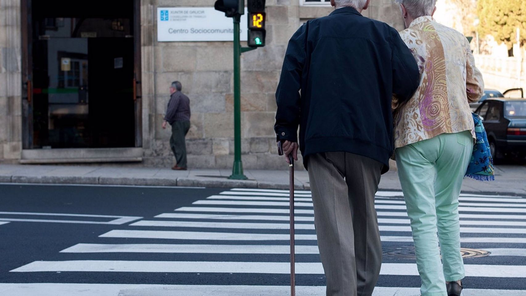 Una pareja de ancianos cruza una calle en Galicia