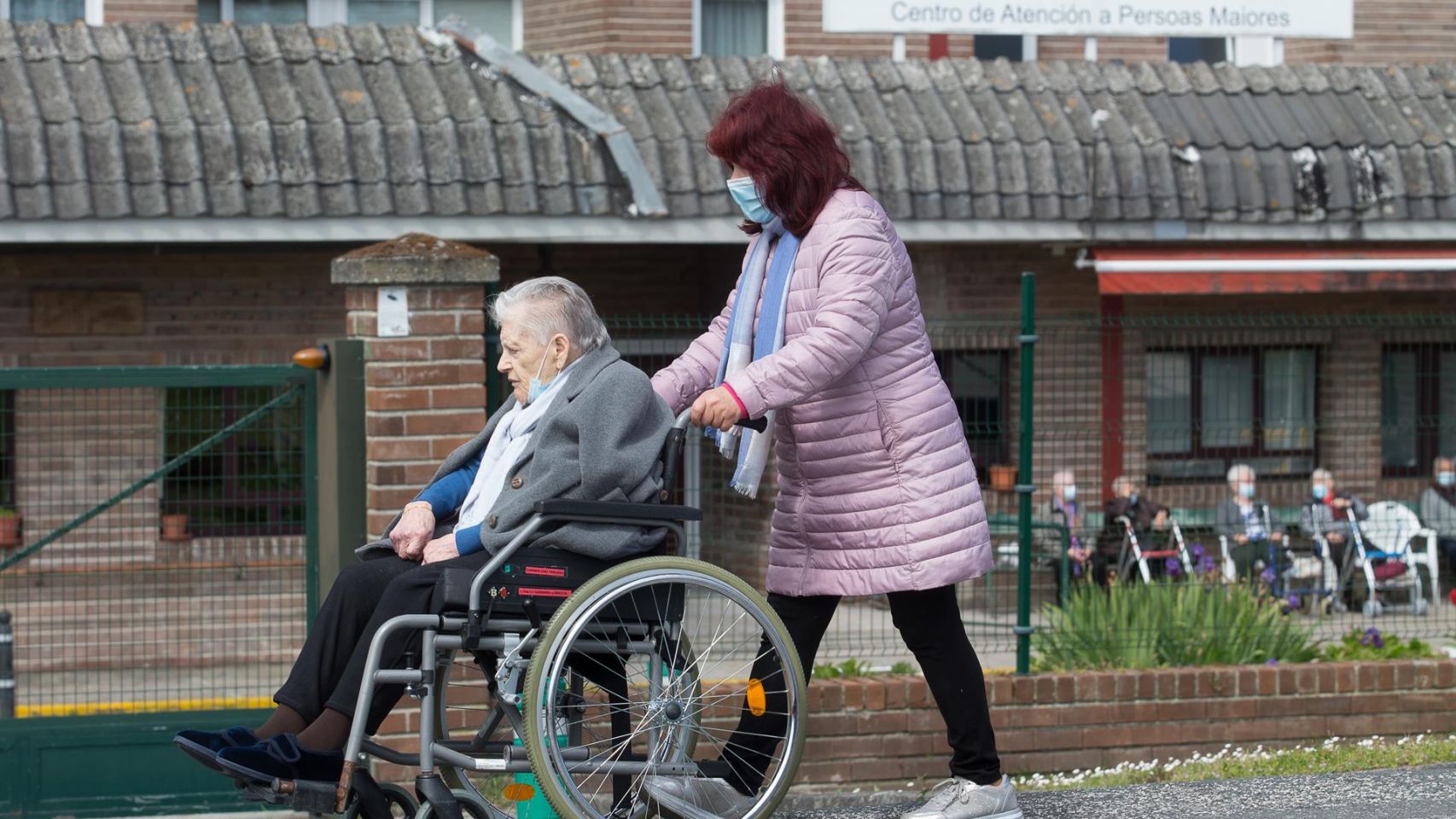 Una mujer pasea a una anciana en silla de ruedas, en las inmediaciones de la residencia geriátrica de As Gándaras (Lugo).