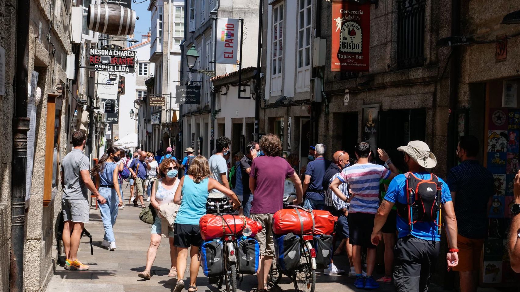 Varios peregrinos caminan con su bicicleta por la Rúa do Franco.