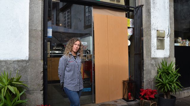 La propietaria de A Carrilana, Natalia Devesa, junto a la puerta destrozada.