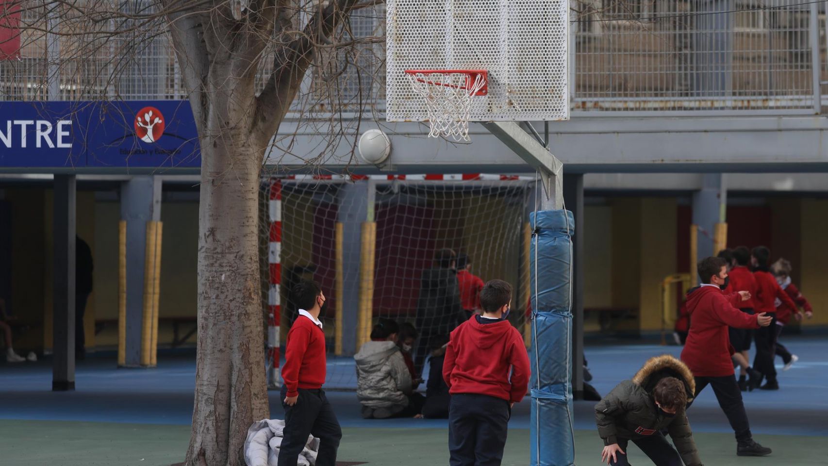 Varios niños juegan al baloncesto en un colegio.