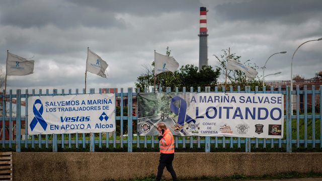 Una persona pasa delante de una pancarta colocada por los trabajadores en la valla de la fábrica de Alcoa en San Cibrao, en una foto de archivo.
