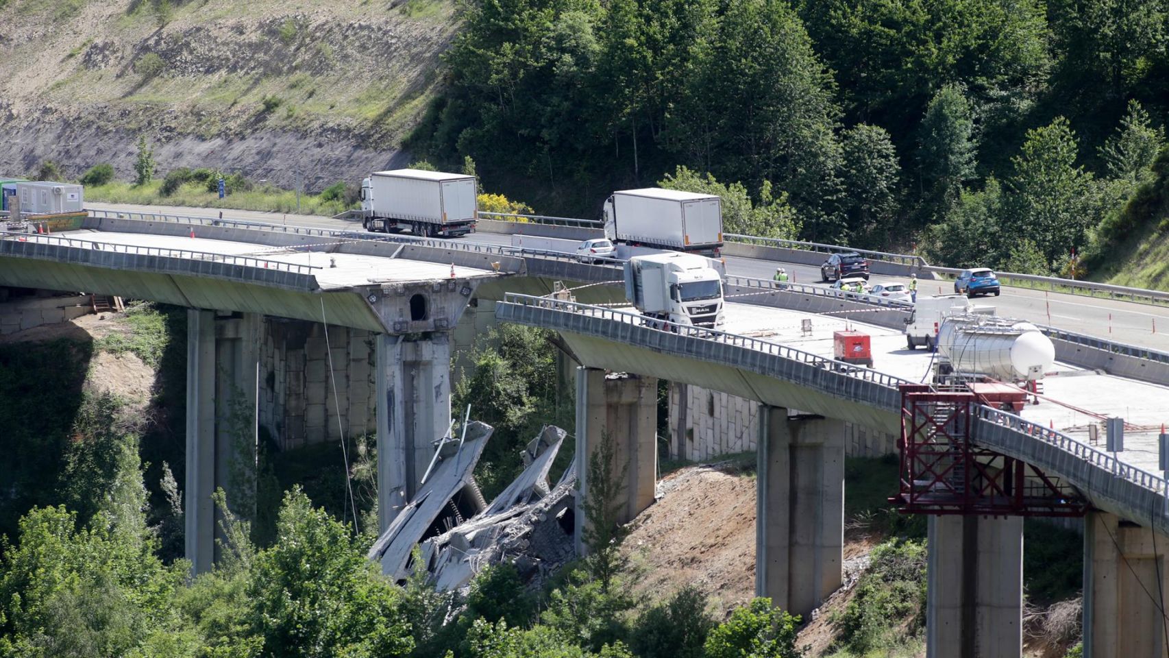 Varios vehículos circulan por la zona de arriba de donde se ha desprendido la parte de un puente.