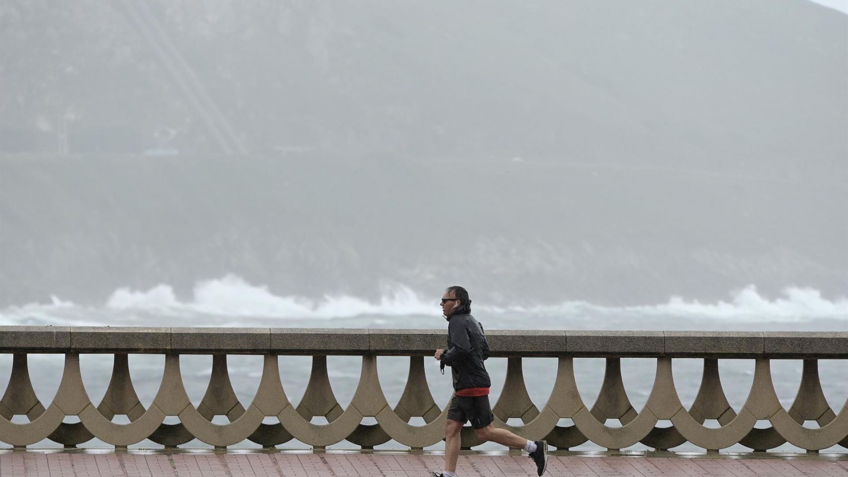 Un hombre, con chubasquero, corre por el Paseo Marítimo de A Coruña en una foto de archivo.