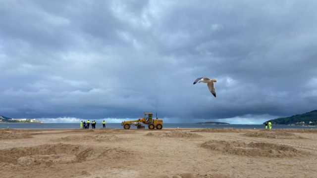 Operarios limpiando el arenal de Playa América tras la celebración de las hogueras de San Juan.
