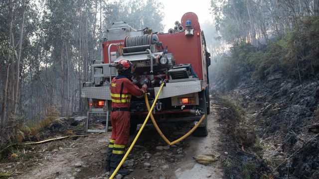 Bomberos trabajan en la extinción de un incendio iniciado en Boiro (A Coruña). 