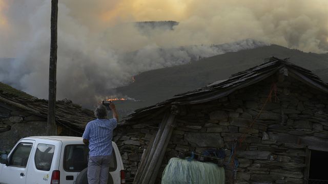Un hombre fotografía las llamas del incendio, a 10 de agosto de 2022, en Laza, Ourense, Galicia (España).