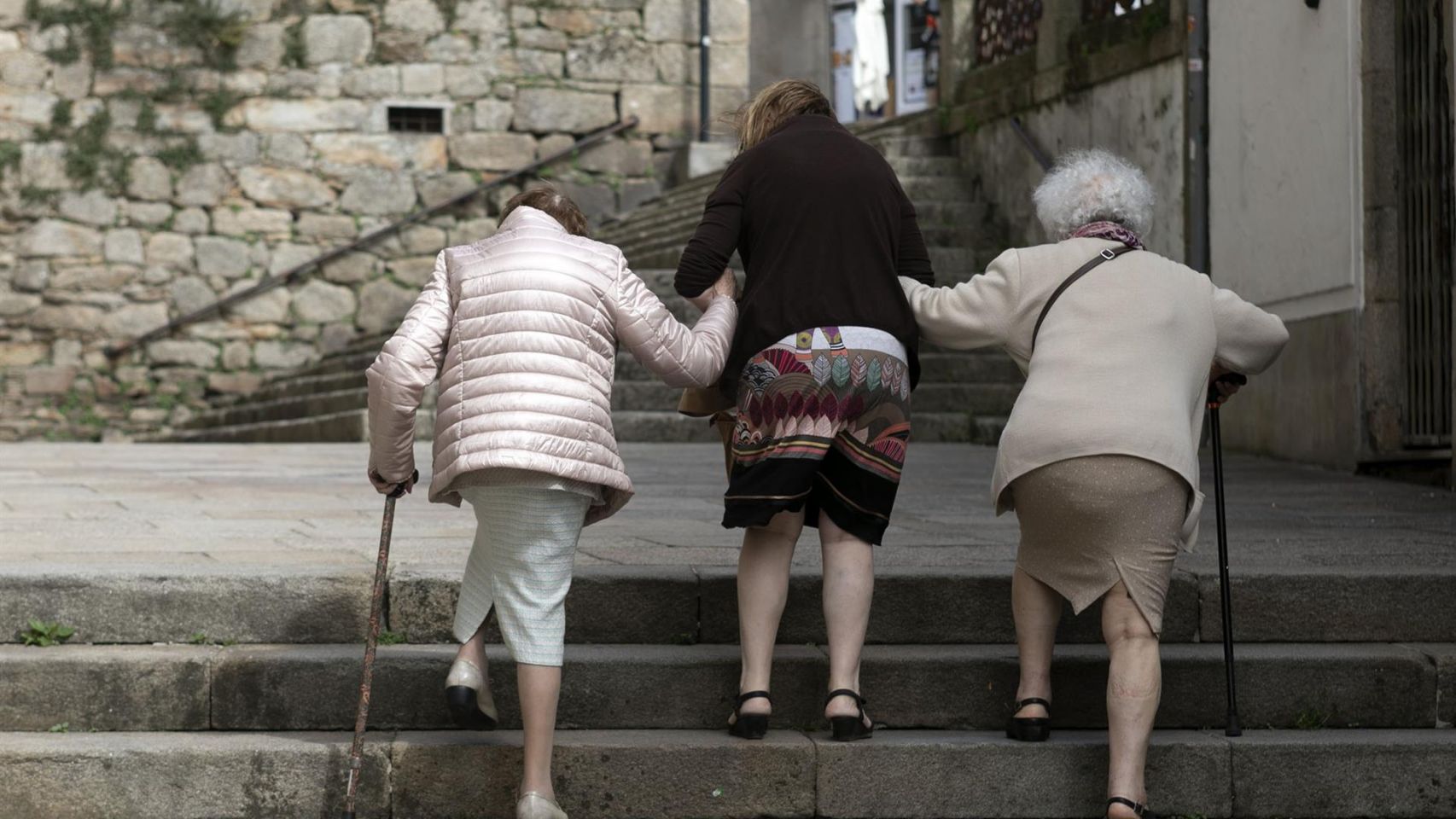 Personas mayores caminan por una calle en Galicia.