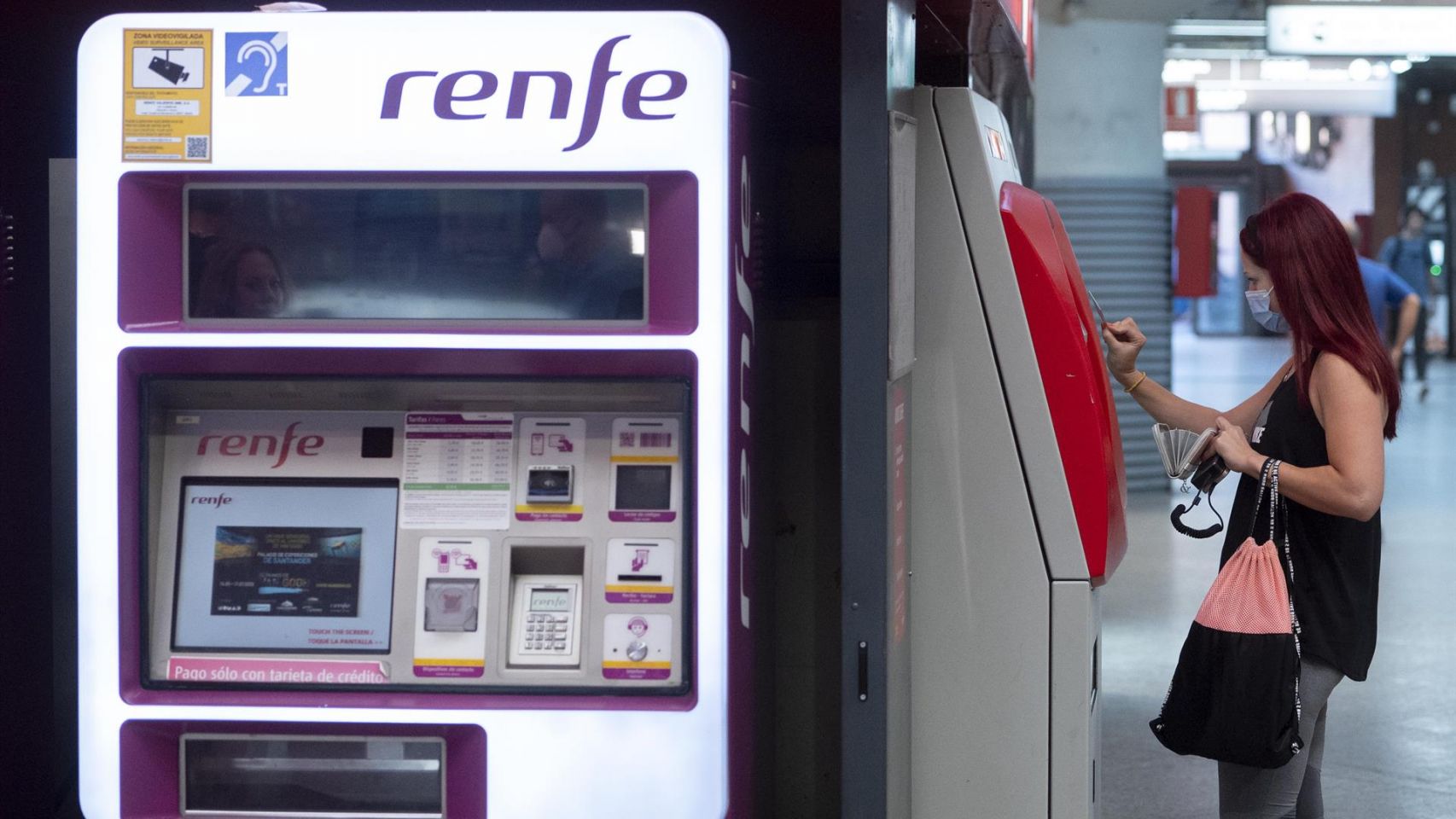 Una mujer compra su billete en las taquillas de venta automática de Renfe.