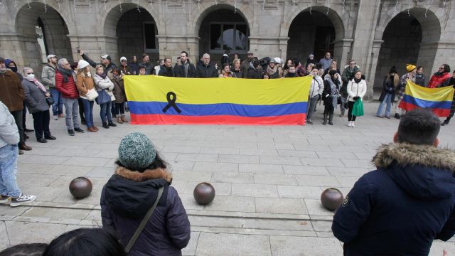 Varias personas portan una bandera de Colombia con un lazo negro durante una concentración en repulsa por el asesinato de Cristina Cabo en Lugo.