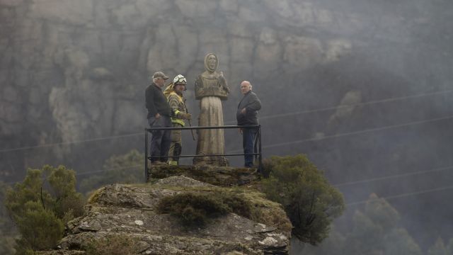 Dos hombres y un guarda forestal observan el monte quemado.