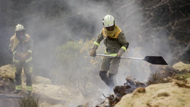 Dos brigadistas forestales trabajan para extinguir las llamas en un incendio forestal, a 30 de marzo de 2023, en Baleira (Lugo).