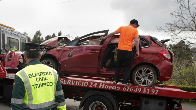Un Guardia Civil vigila la retirada del coche siniestrado, en el accidente de Xove (Lugo).