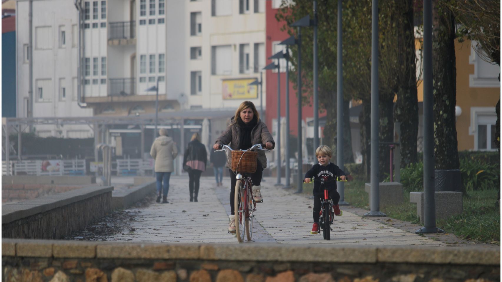 Una mujer pasea en bicicleta con su hijo en un pueblo de Galicia