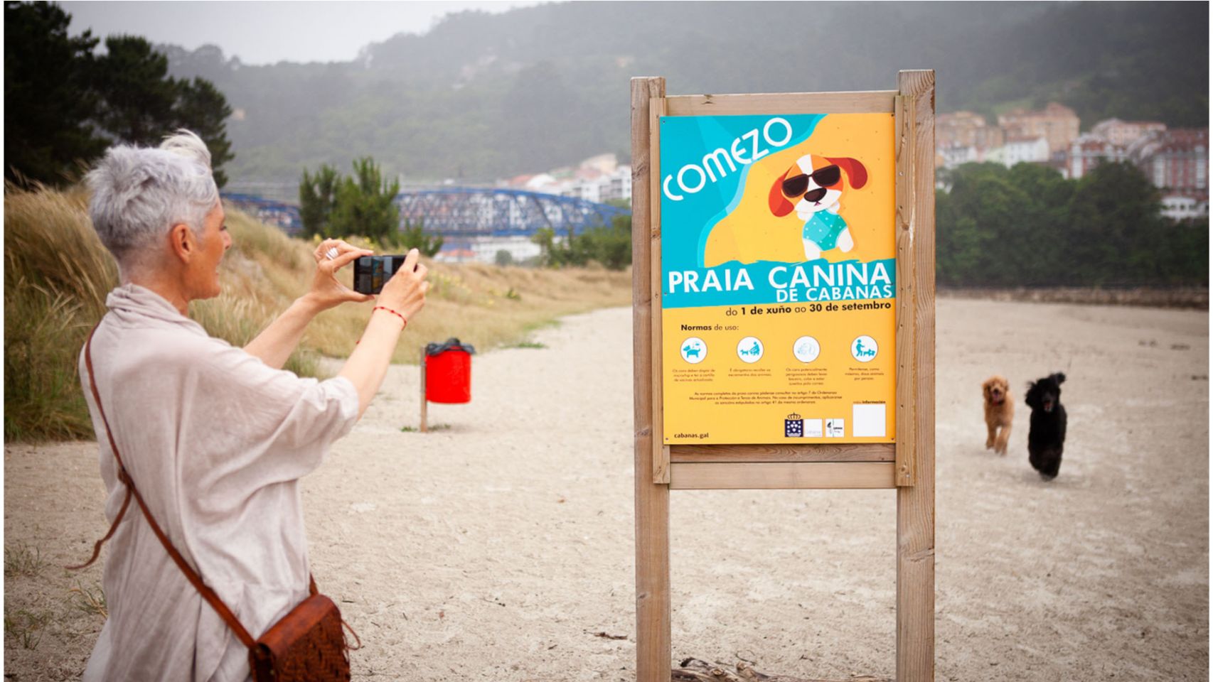 Una mujer fotografía el cartel de la playa canina de Cabanas