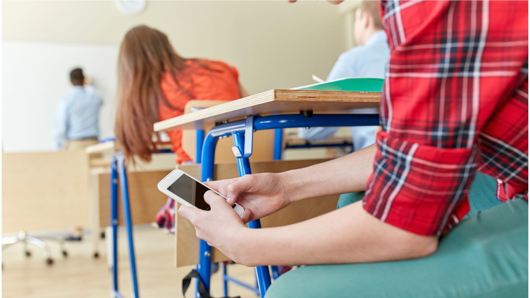 Un alumno usa el móvil en el aula