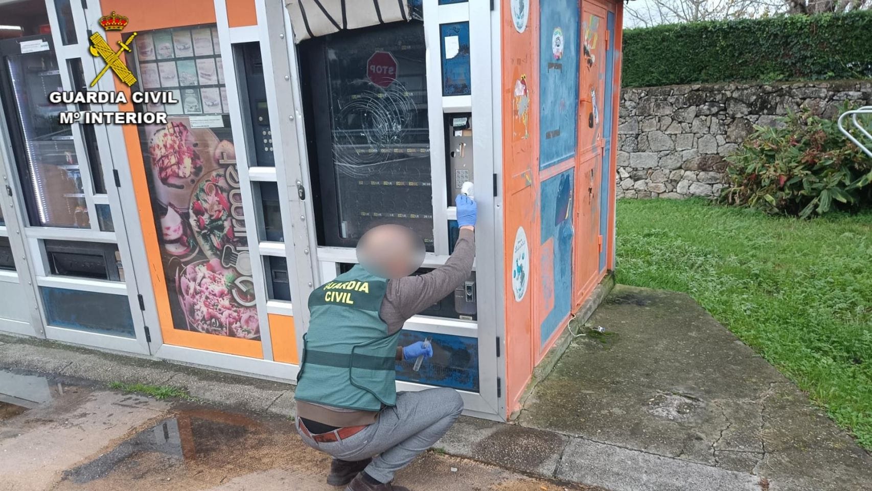 Un investigador de la Guardia Civil toma huellas en una máquina expendedora.