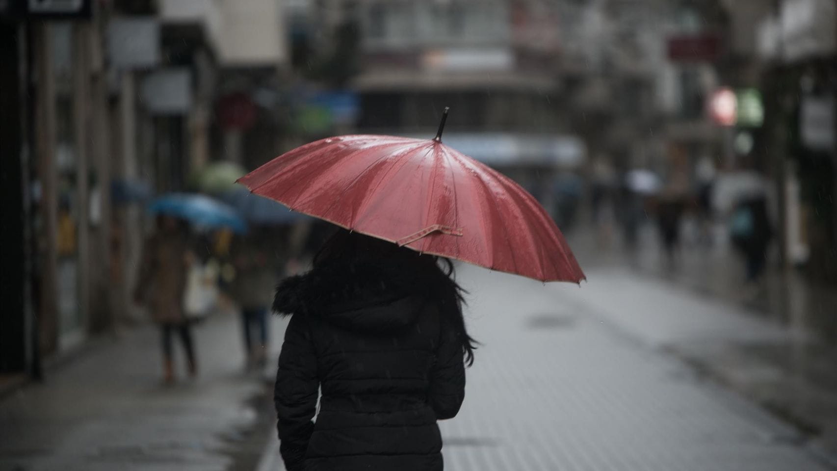 Una persona se resguarda de la lluvia en una imagen de archivo. 