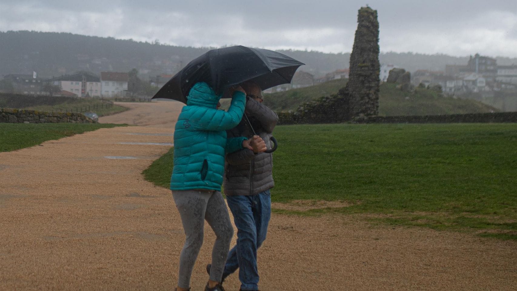 Dos personas se protegen de la lluvia con un paraguas, en la playa de A Lanzada, a 5 de noviembre de 2023.